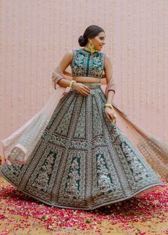 a woman in a blue and green lehenga standing on a bed of flowers