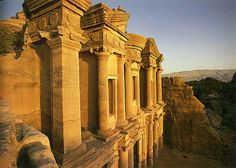 an ancient building in the middle of a cliff side area with columns and pillars on it's sides