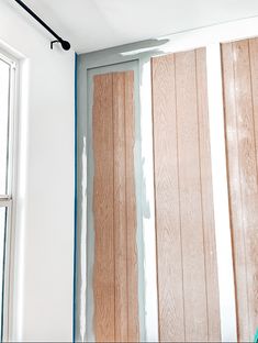 an unfinished room with wood paneling on the wall and window frames being painted white