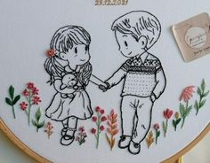 two children are holding hands in front of a floral embroidery pattern on a hoop frame