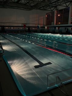 an empty swimming pool at night with the lights on and no one in it yet