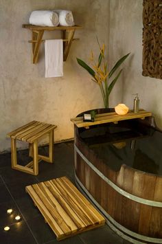 a bathroom with a large wooden tub next to two stools and a towel rack