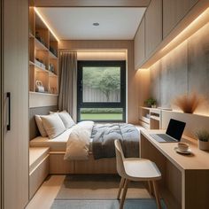 a bedroom with a bed, desk and laptop computer