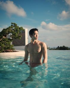 a shirtless man standing in the middle of a swimming pool with his hands on his hips