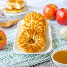 an apple pie on a white plate next to some apples and other food items with spoons