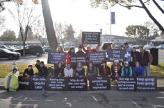 a group of people holding up signs on the side of a road with trees in the background