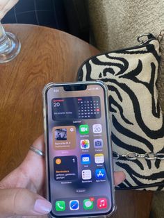 a person holding an iphone in their left hand and a zebra print bag on the other