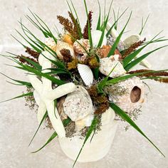 a vase filled with lots of different types of flowers and seashells on top of snow