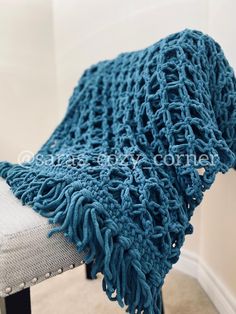 a blue crocheted blanket sitting on top of a white chair next to a wall