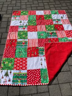 a red and green patchwork quilt on the ground