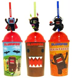 three plastic cups with toothbrushes and monsters on them are lined up in a row