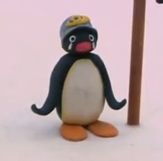 a toy penguin wearing a hat standing next to a pole