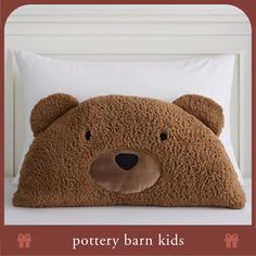 a brown teddy bear pillow sitting on top of a bed