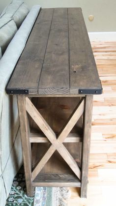 a wooden table sitting on top of a hard wood floor next to a gray couch