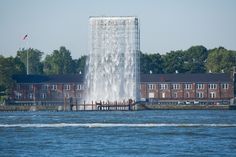 there is a large water fountain in the middle of the lake with people on it