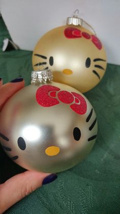 two christmas ornaments with hello kitty designs on them are being held by a woman's hand