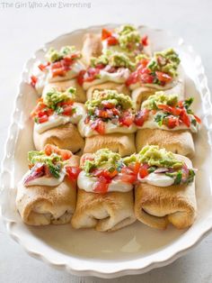 a white plate topped with rolls covered in guacamole and salsa toppings