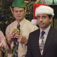 three men wearing christmas hats standing next to each other in front of a christmas tree