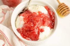 a bowl filled with ice cream next to a jar of honey and a wooden spoon