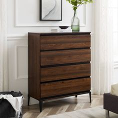 a wooden dresser sitting in front of a window next to a painting on the wall