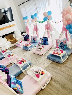 a living room filled with lots of pink and blue balloons on top of couches