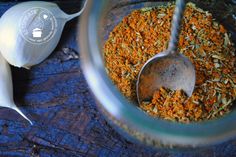 an image of spices in a jar with spoons on the side and garlic flakes next to it