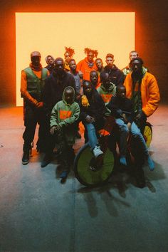 a group of people standing next to each other in front of a yellow wall with masks on