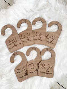 four wooden baby bibs with numbers and date on them sitting on a white furnishing