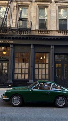 a green car parked in front of a tall building