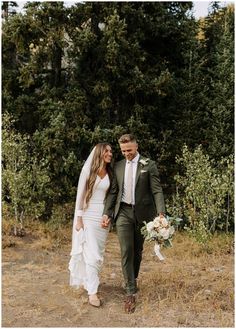 a bride and groom walking through the woods