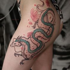 a woman's thigh with a dragon tattoo on the side and flowers around it