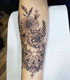 a black and white flower tattoo on the left arm, with an arrow in the middle