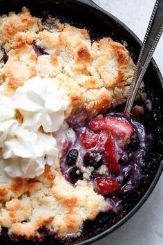 blueberry cobbler with whipped cream in a cast iron skillet