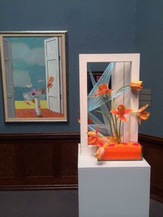 there is a vase with flowers in it and an open door on the wall behind it