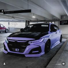 a purple car parked in a parking garage next to another red car on the street