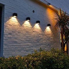 four lights on the side of a white brick building