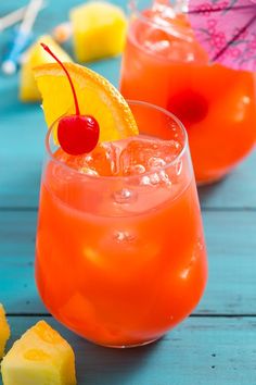 two glasses filled with orange juice and topped with a cherry