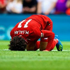 a soccer player is on the ground with his head in his hands while looking down