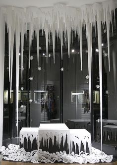 icicles are hanging from the ceiling in front of a store window with tables and benches