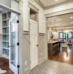 an open door leading to a kitchen and dining room area with hardwood floors, white walls and cabinets