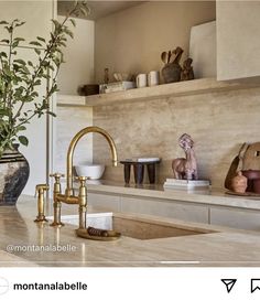 a kitchen counter with gold faucet and vases on the shelf above it