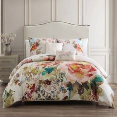 a bed with floral comforter and pillows on it