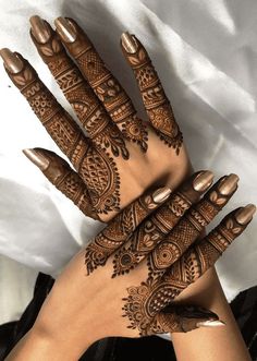 hendi tattoos on the hands of a woman with brown nails and gold nail polish