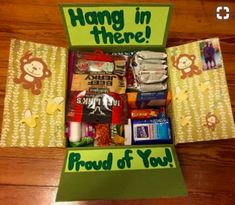 an open box with various items in it on a table next to a sign that says, hang in there proud of you