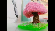 a pink tree with green grass on the ground