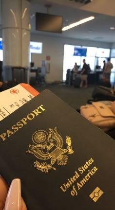 a passport being held in front of people at an airport with suitcases and luggage behind them