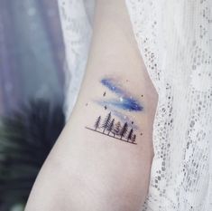 a woman's arm with trees and stars on it