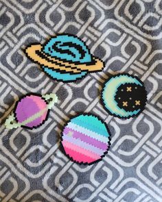 three pieces of bead art on a gray and white fabric with an image of the solar system