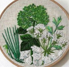 an embroidery project with white flowers and green leaves