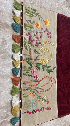 a close up of a piece of cloth with tassels and flowers on it